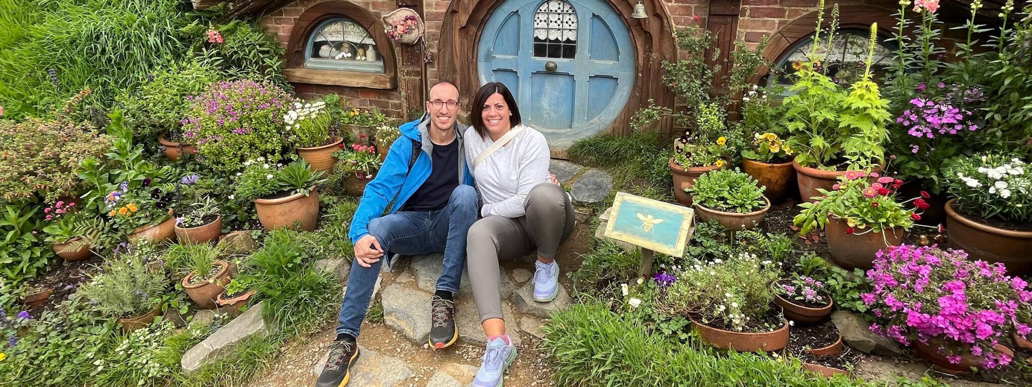 Una pareja frente a una casa hobbit en Hobbiton