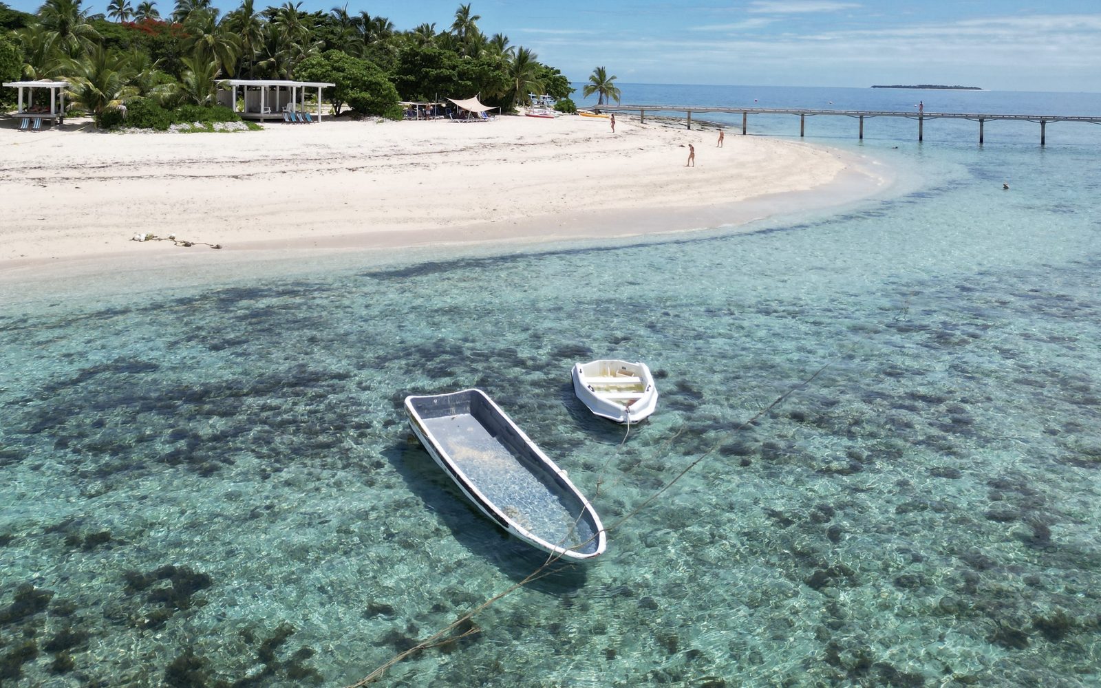 Playa de arena blanca con barcas en el agua turquesa de Fiyi
